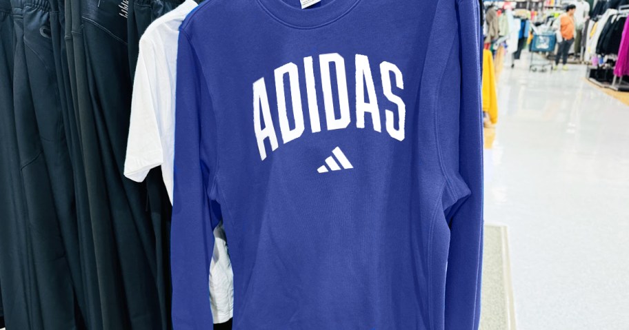 blue adidas sweatshirt on a hanger in store