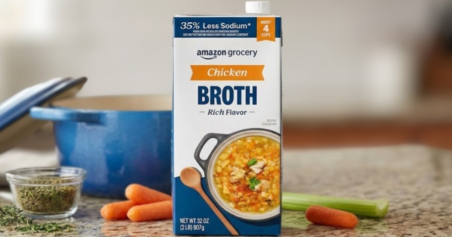 bottle of amazon grocery low sodium chicken broth on kitchen counter with dutch oven and carrots and celery