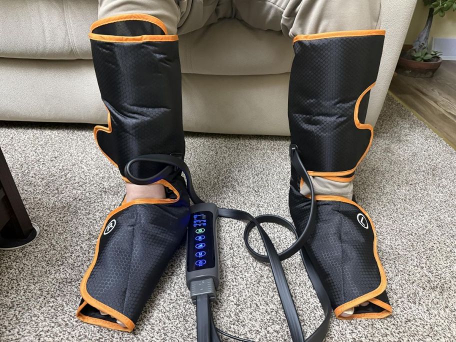 A person wearing a black and orange leg massager