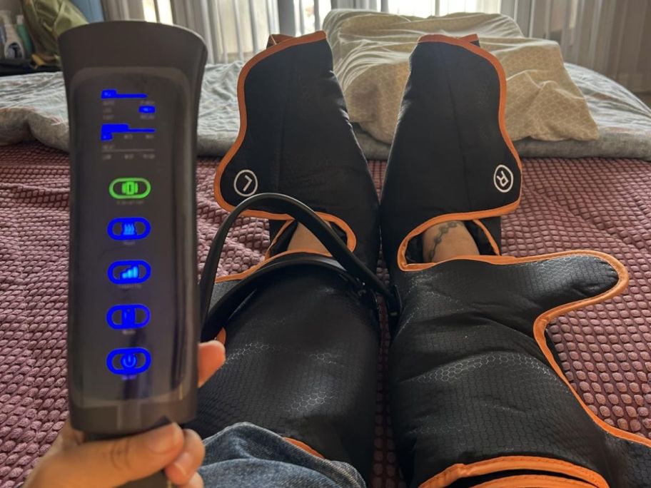 A person wearing a black and orange leg massager