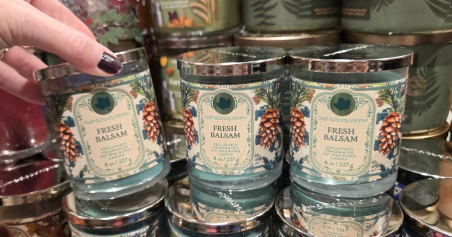 Hand reaching for Bath and Body Works Fresh Balsam candles