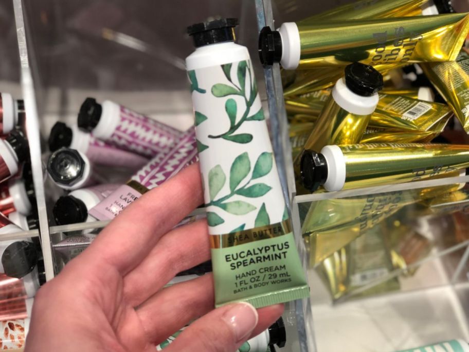 Hand holding a tube of Eucalyptus Spearmint Bath & Body Works Hand Cream