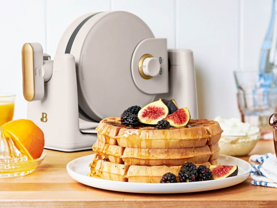 plated stack of waffles with waffle maker in background