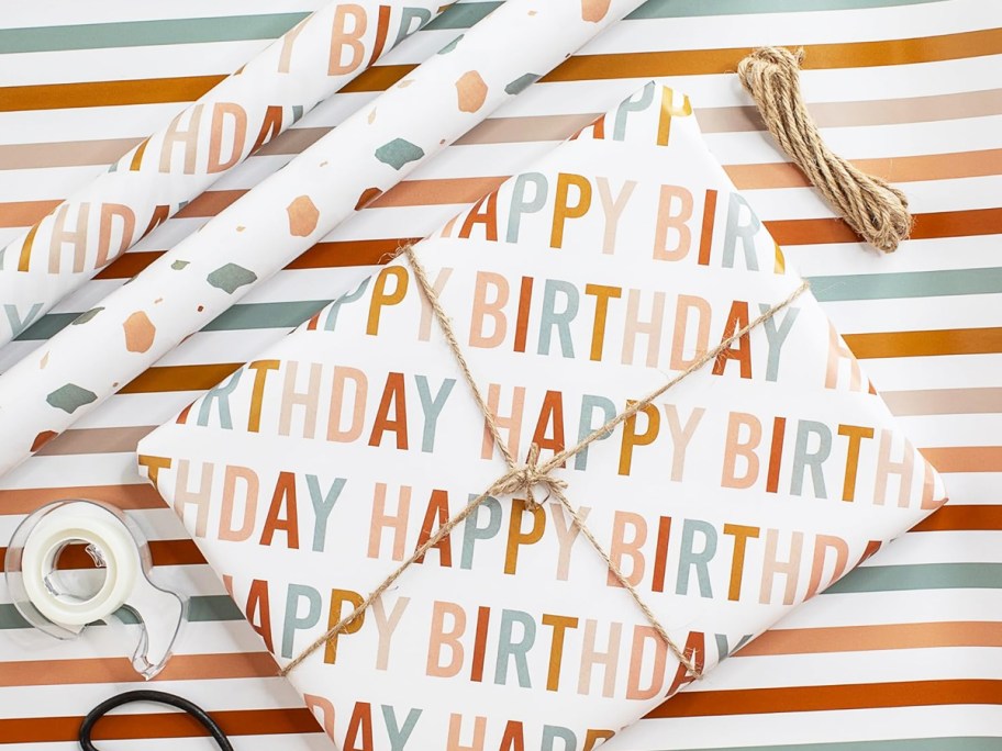 gift wrapped in birthday paper near rolls of wrapping paper