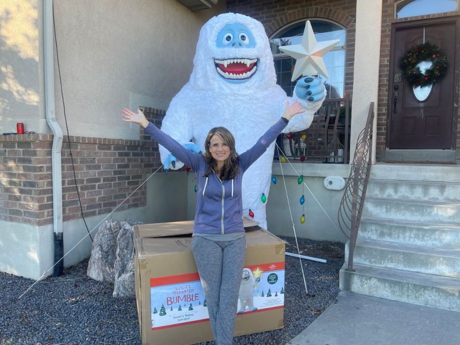 woman standing outside with a huge Bumble snowman and boxes displayed 