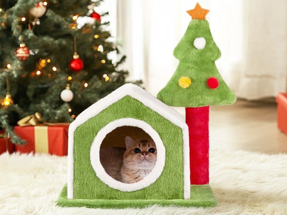 cat inside of a christmas themed cat house and tree