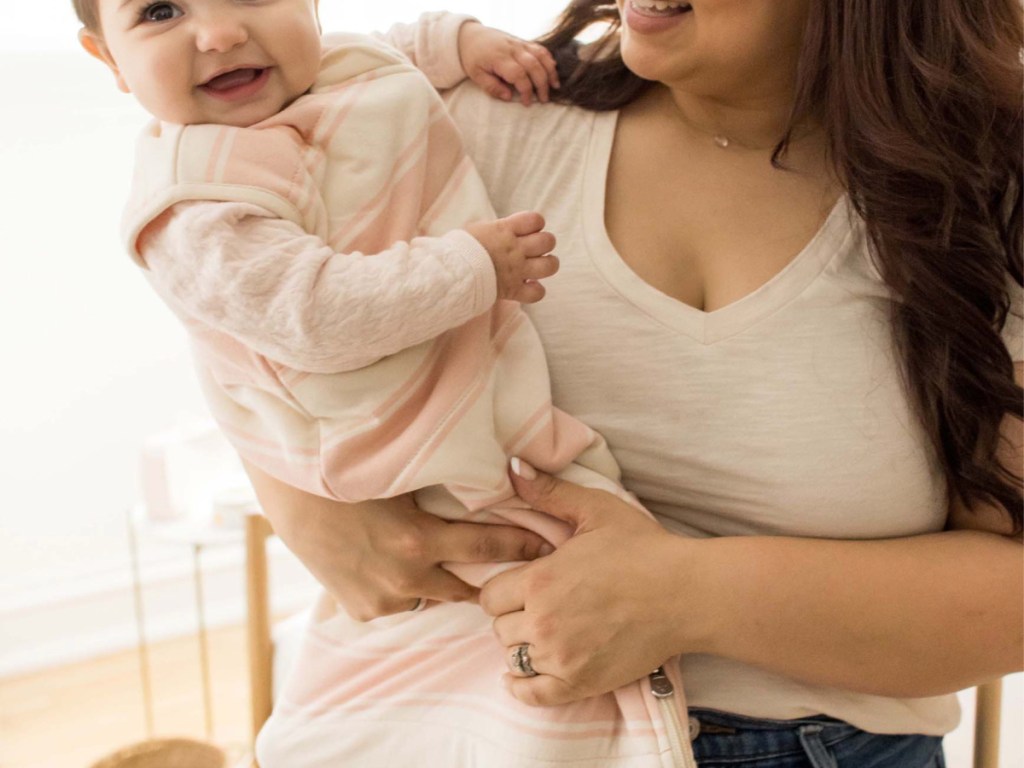 Woman holding baby with pink and white striped baby sleeper
