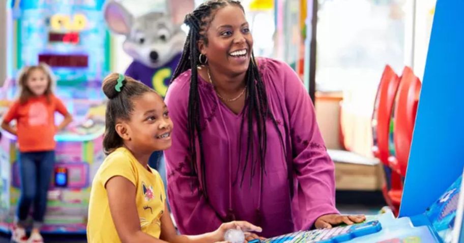 Woman and little girl playing video game at Check E. Cheese