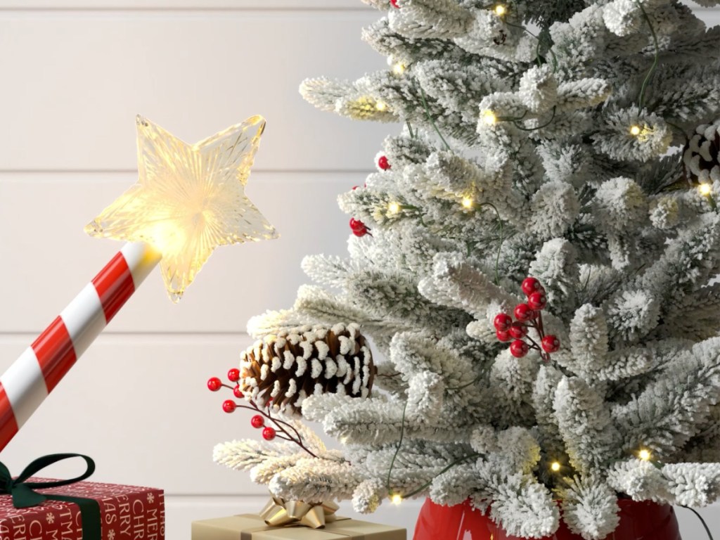 Red and white striped magic Christmas wand pointed at flocked Christmas tree