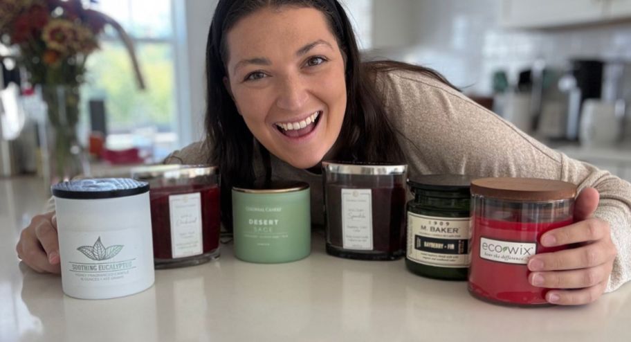 Woman holding 6 different Colonial Candle on top of her kitchen