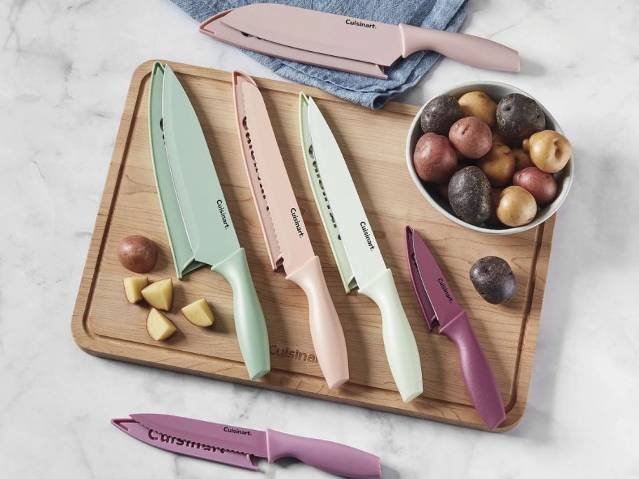 Cuisinart 12 piece knife set displayed on a cutting board with food around it