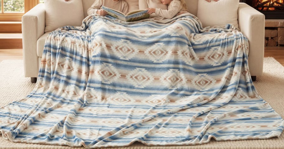 family sitting on couch under a huge blanket