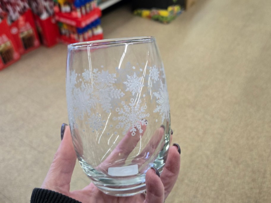 A hand holding up a Christmas glass at Dollar Tree.