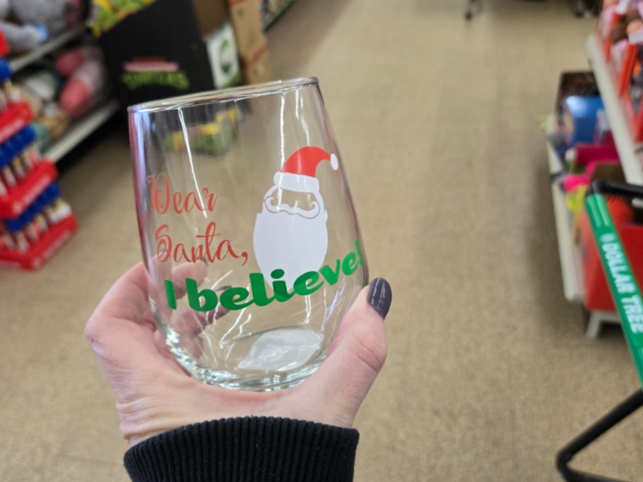 A hand holding up a Christmas glass at Dollar Tree.