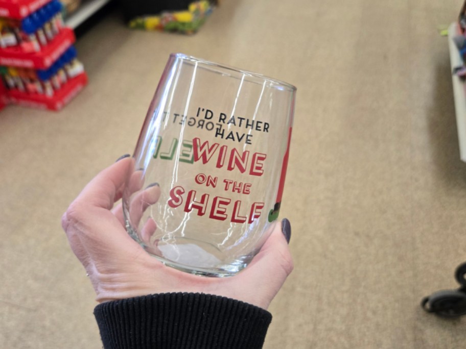 A hand holding up a Christmas glass at Dollar Tree.