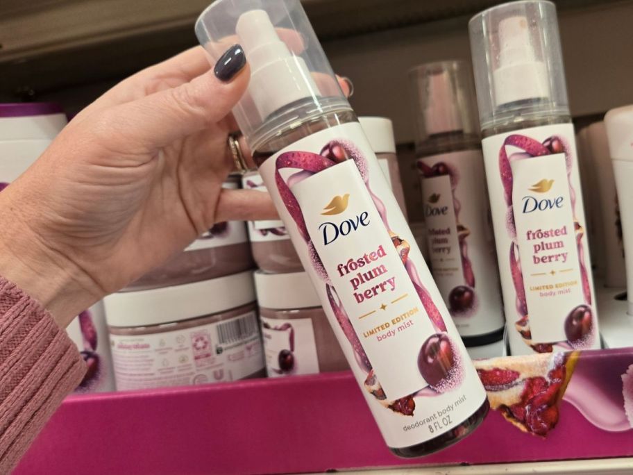 A person holding Dove body spray in a store