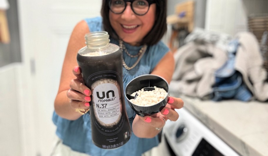 Woman holding container of Downy unstoppables while standing in laundry room