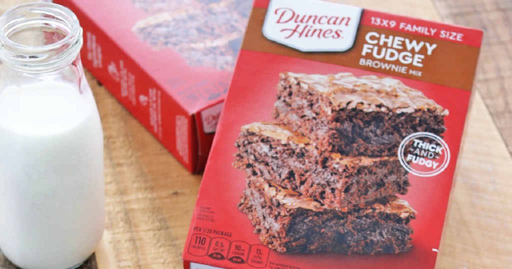 Boxes of Duncan Heinz brownie mix on wooden table next to jug of milk