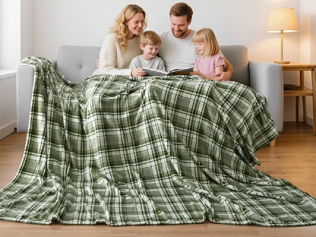 Large green plaid blanket covering entire family while sitting on couch
