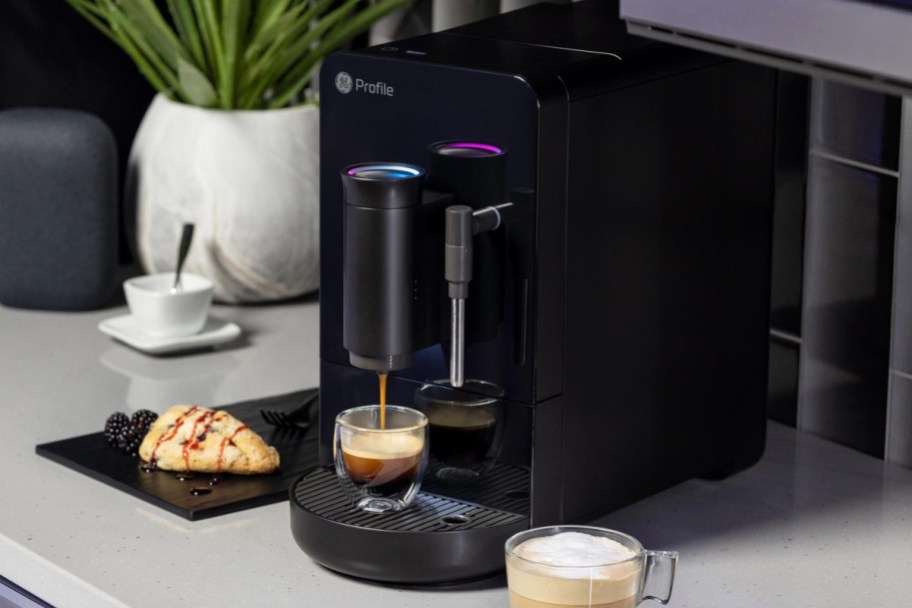 black espresso machine dripping espresso next to coffee mug