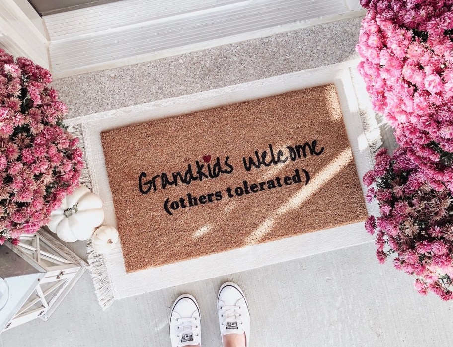 grandkids welcome others tolerated doormat on porch with pink mum flowers