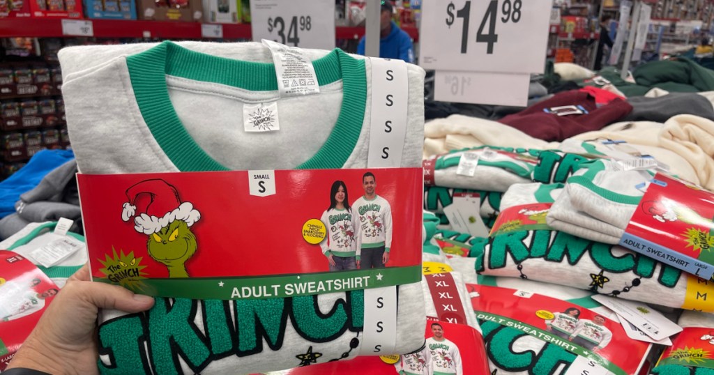 Person holding up grinch sweatshirt inside Sam's Club store