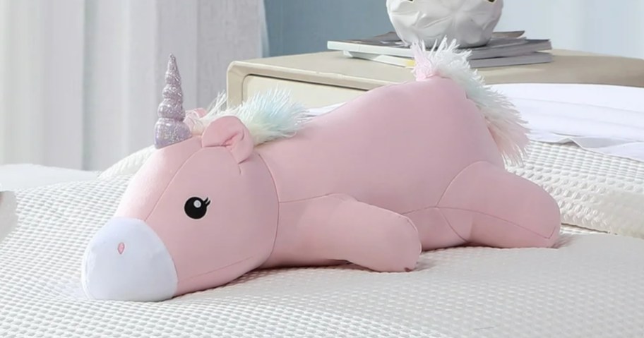 a plush unicorn pillow on a bed