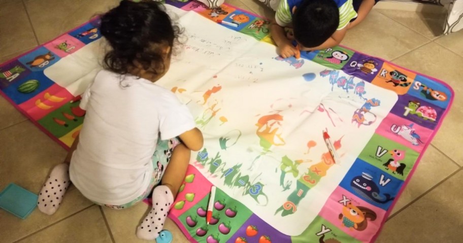 two kids playing on a water doodle mat