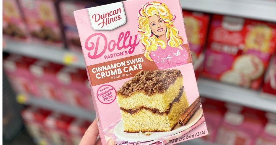 hand holding a box of Duncan Hines Dolly Parton's Cinnamon Swirl Crumb Cake & Muffin Mix