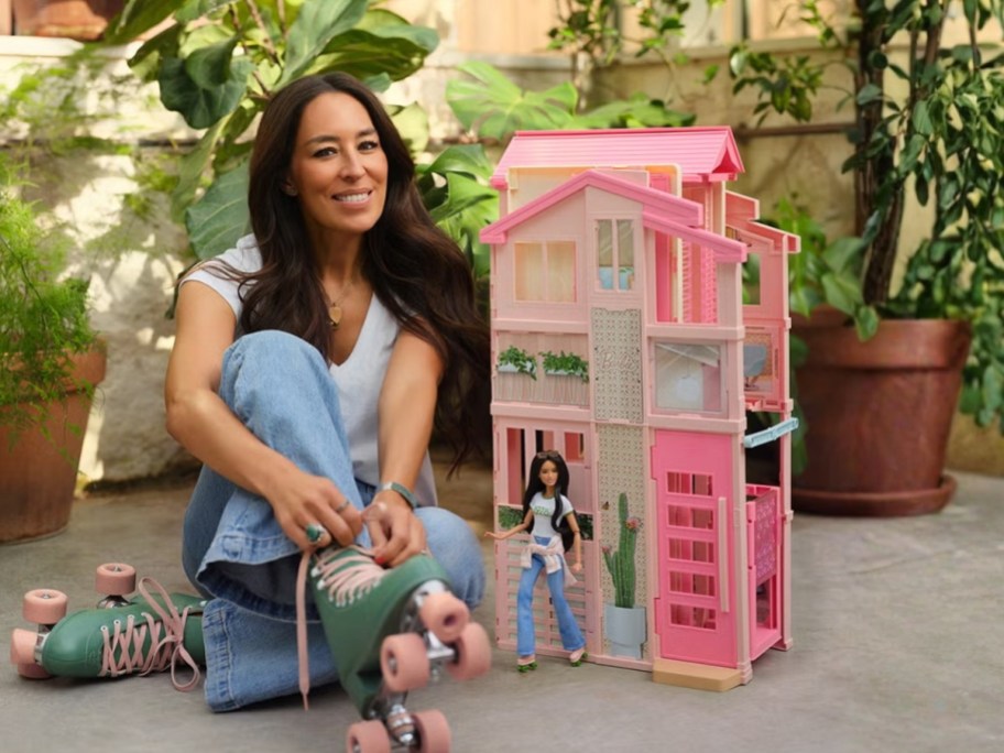 Joanna Gaines (woman) sitting next to a Joanna Gaines Barbie doll and a Barbie Hearth & Hand House