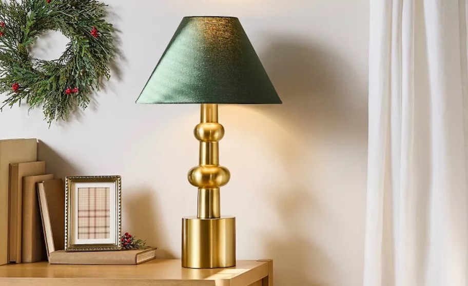 gold and green lamp on side table with wreath on door