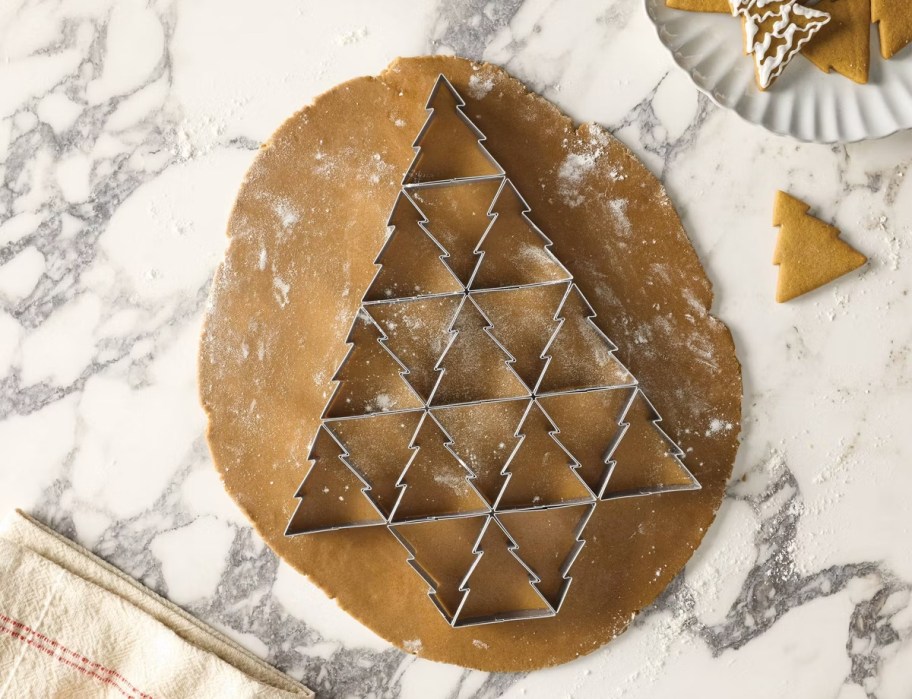 cookie tree cutter on gingerbread dough on marble counter