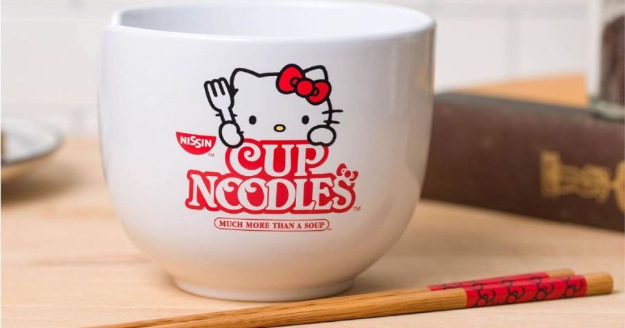 A Hello Kitty bowl with chopsticks on a table 