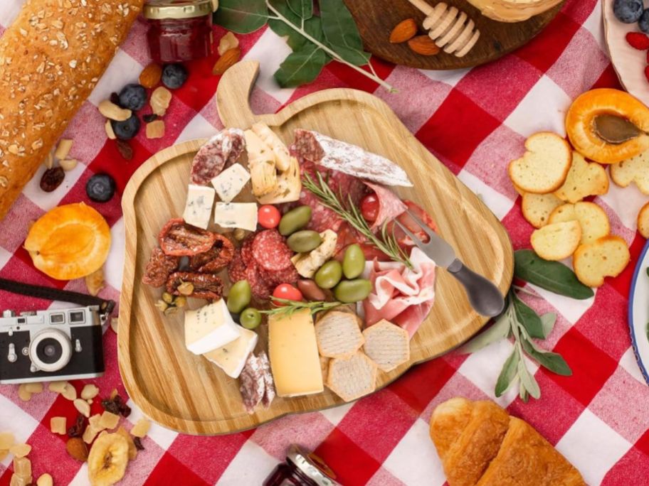 A pumpkin shaped cutting board with charcuterie elements on it