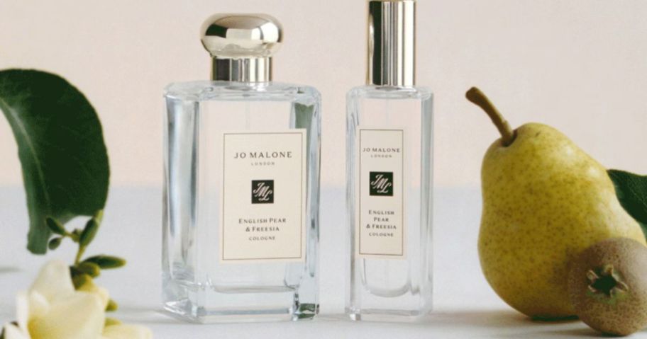2 clear fragrance bottles surrounded by pears