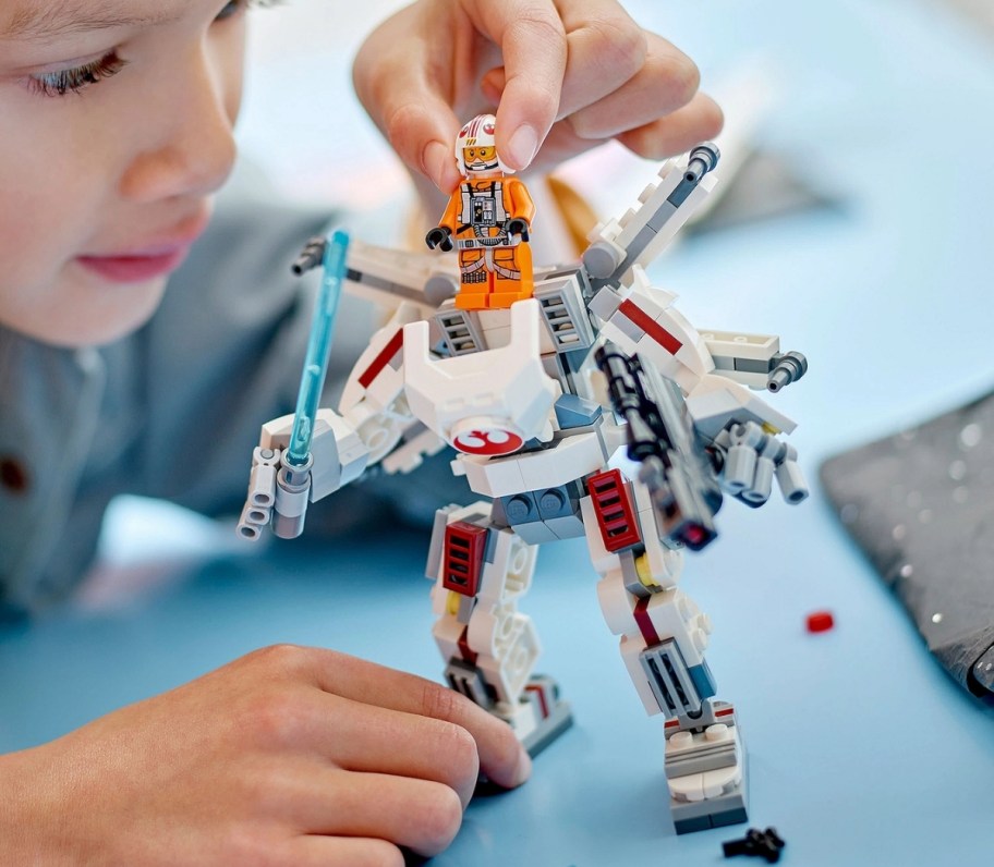 a little boy playing with a lego action figure
