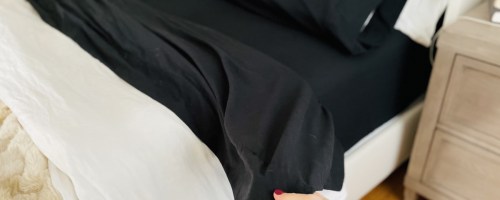 Black sheets on bed with white comforter