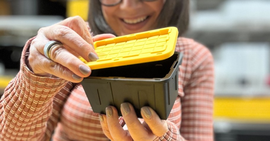 woman holding a tiny black tote with a yellow lid
