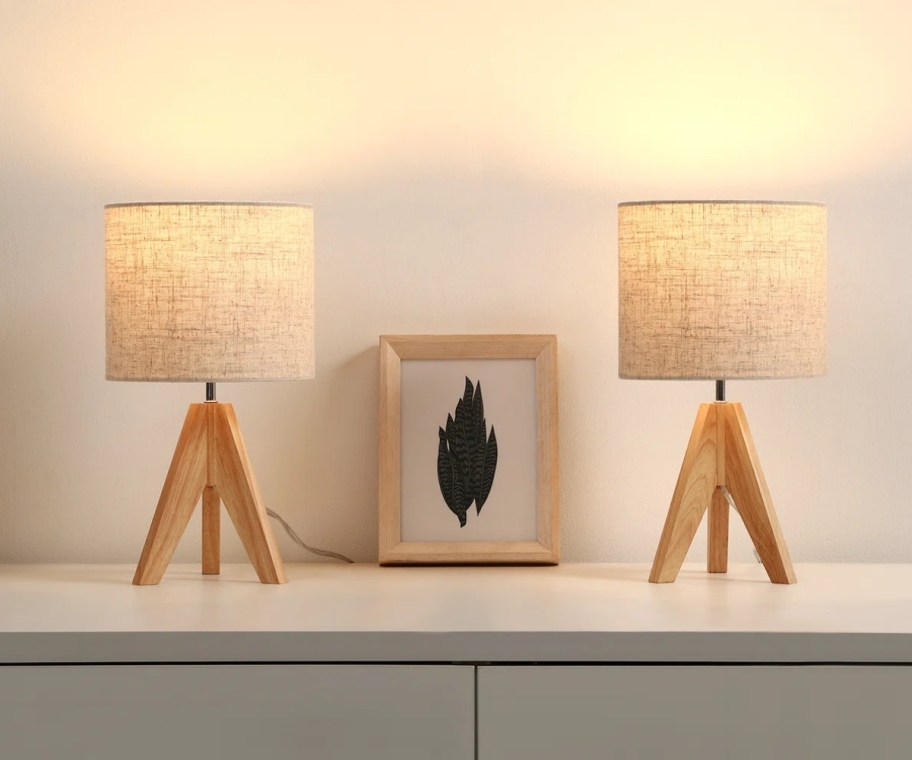 2 table lamps on a console table with a framed print