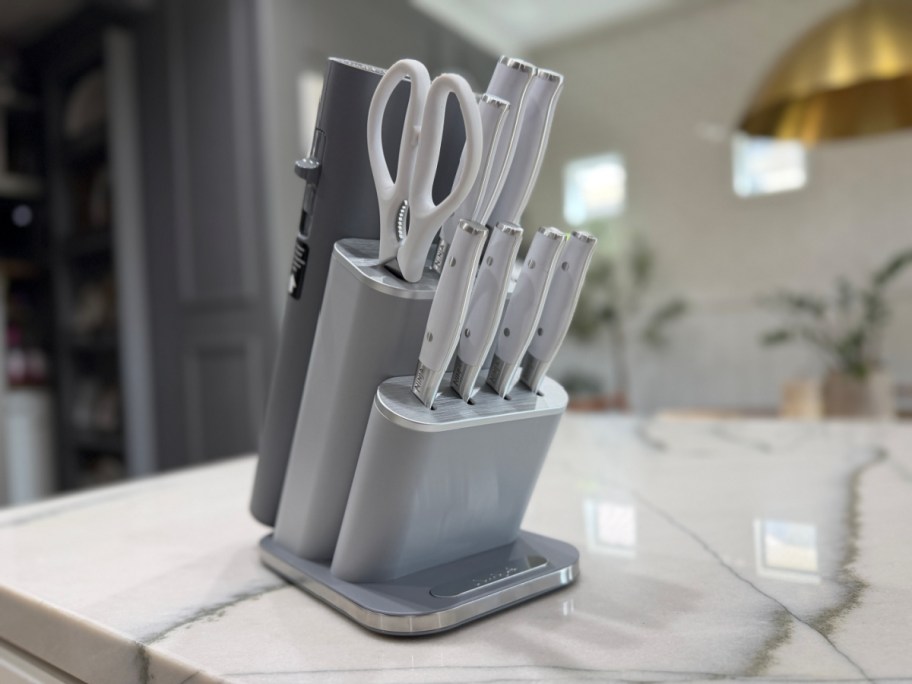 Ninja Foodi NeverDull knife set with white handles in a grey block sitting on a marble countertop.