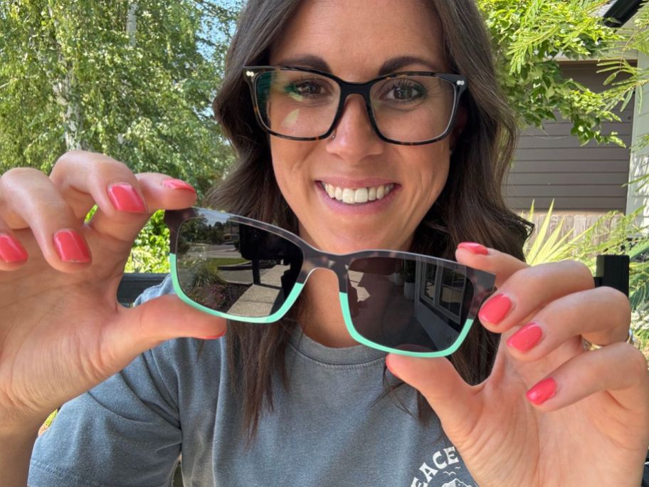 Woman holding Pair frame toppers in front of her eye glasses