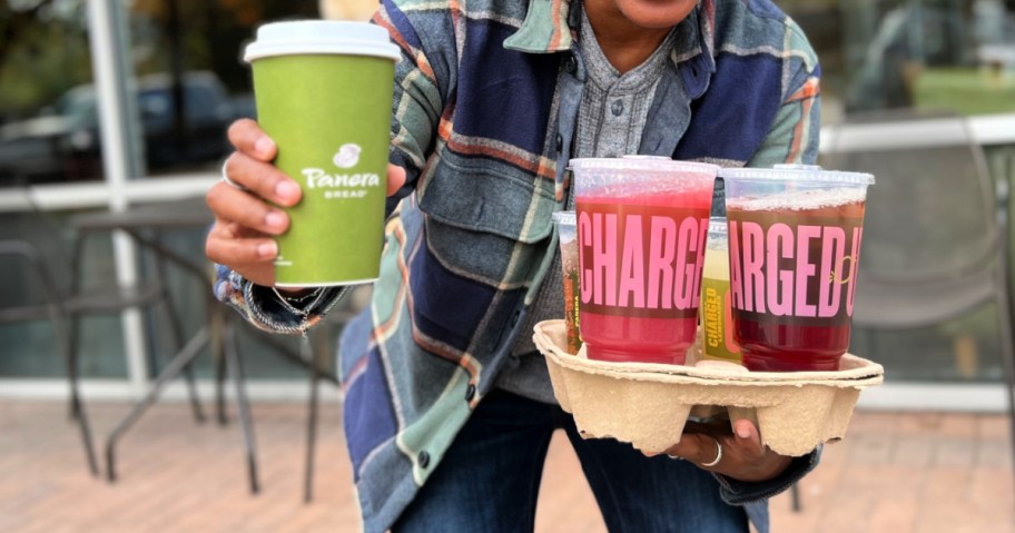 Person holding up several different Panera drinks in drink carrier while standing outside