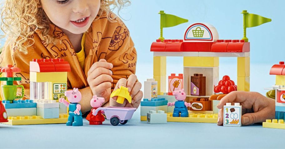 A child playing with a Peppa Pig LEGO Duplo set