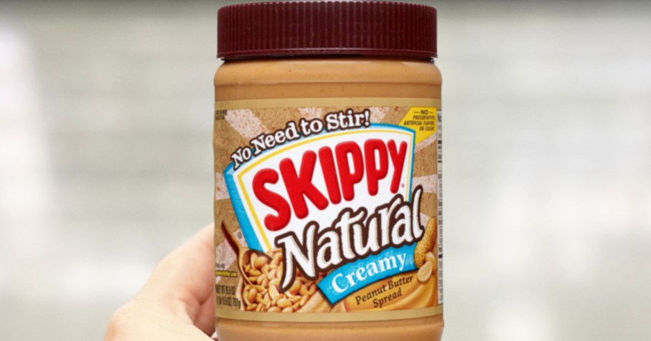 hand holding a jar of SKIPPY Natural Peanut Butter