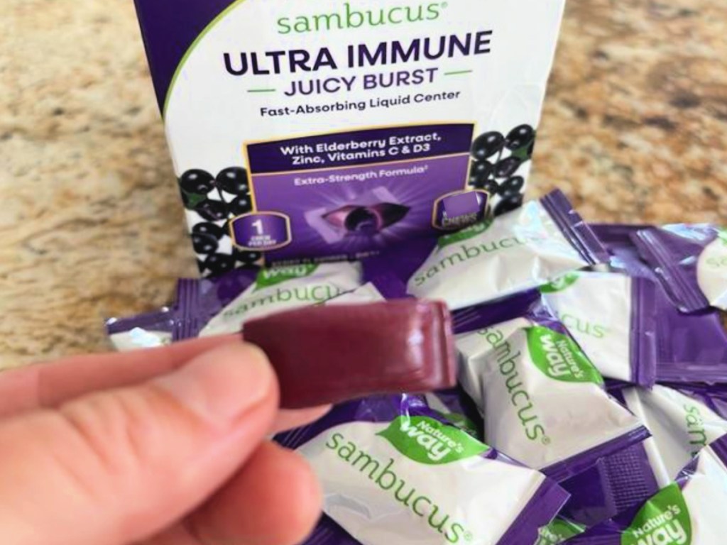 Person holding up juicy burst next to Sambucus box