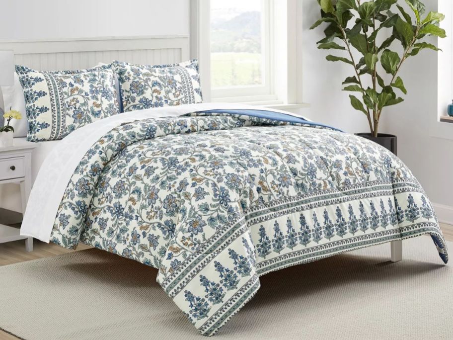 A bed with a blue and white floral comforter on it