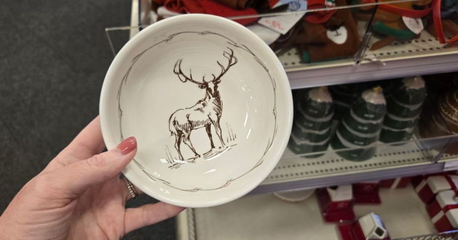 A person holding a ceramic bowl with a deer painted on it