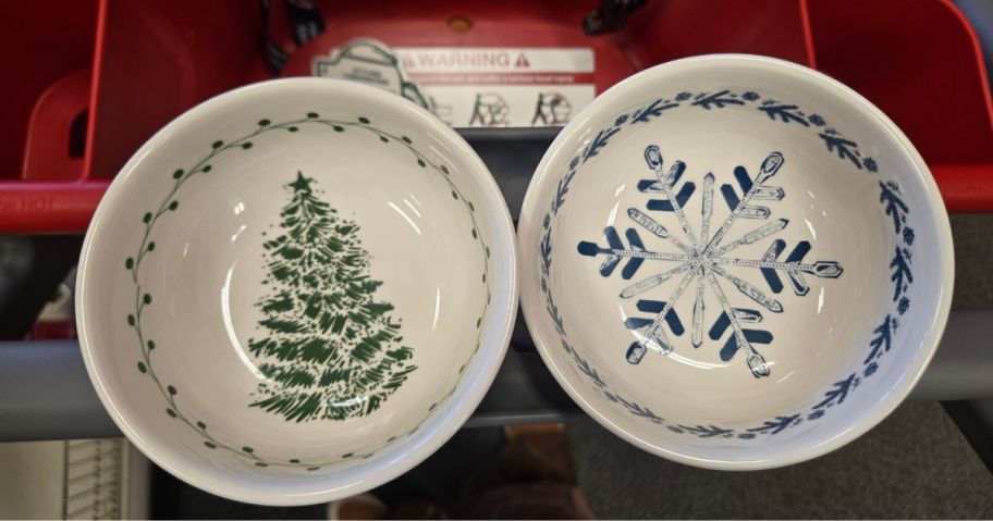 2 ceramic bowls in a cart: one with a Christmas Tree painted on it and the other with a blue snowflake