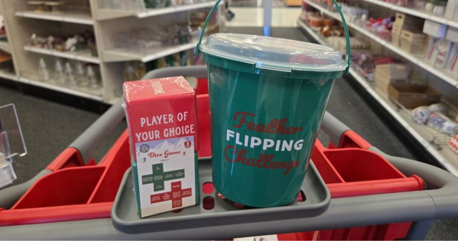 two Christmas games in a cart: one dice and the other a large cup with "flipping feathers' printed on it