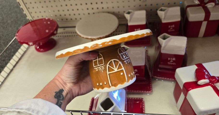 A person holding a brown gingerbread themed ceramic cake stand